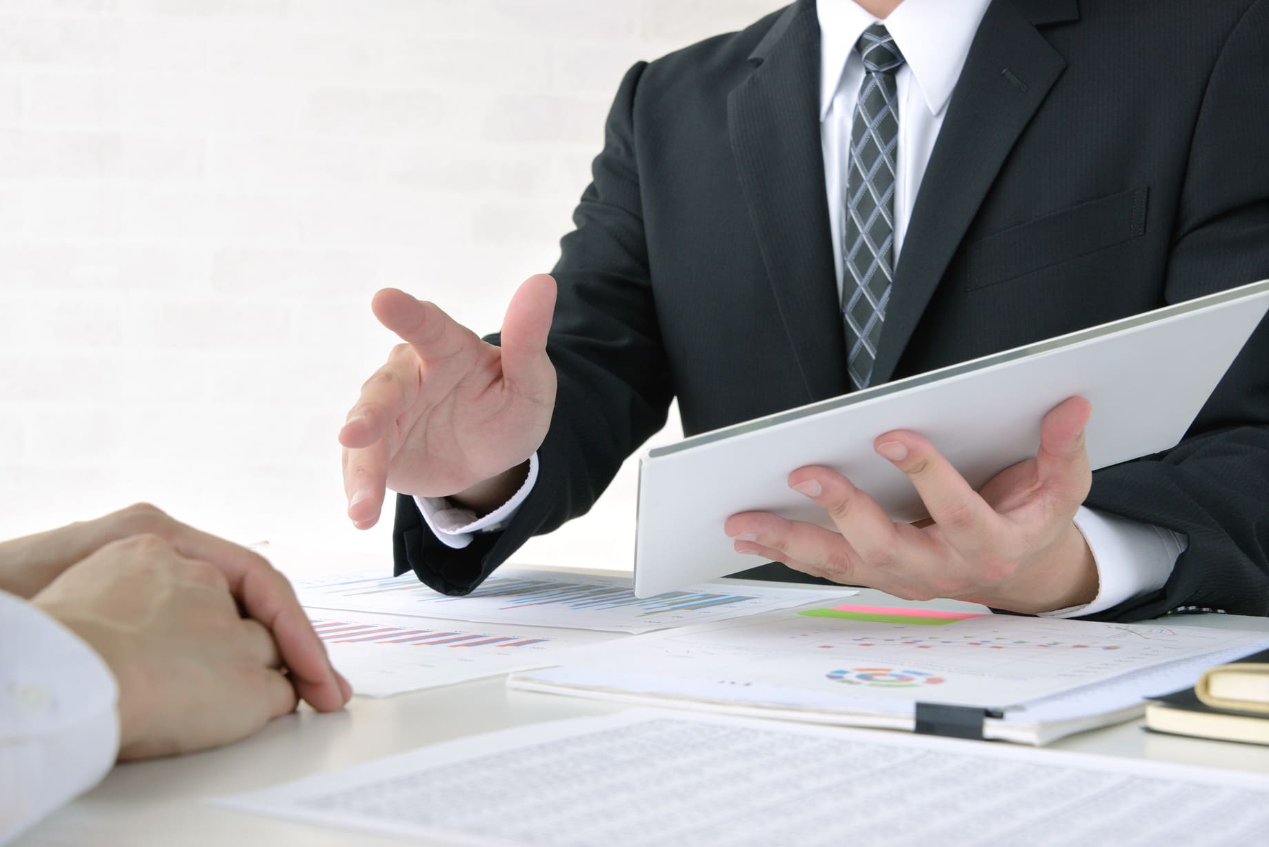 営業マンの男性が資料をもとにプレゼンしている画像